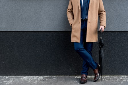 cropped view of businessman holding umbrella and standing with hand in pocketの写真素材
