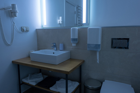 bathroom with washstand, toilet, towels and hair dryerの写真素材