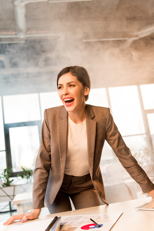 attractive scared woman screaming in office with smokeの写真素材