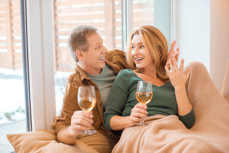 happy couple holding glasses of white wine and looking at each other