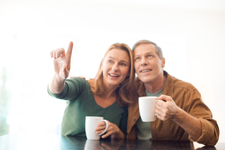 selective focus of couple holding coffee cups while woman pointing with fingerの写真素材