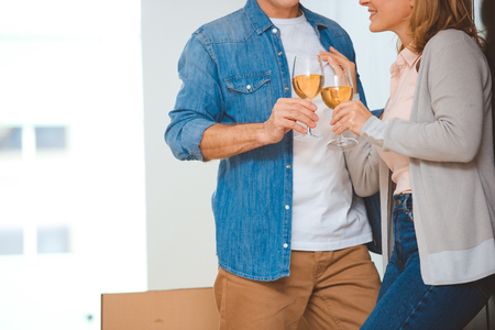 cropped view of couple clinking glasses of white wineの写真素材