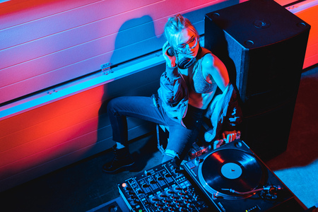overhead view of dj girl with blonde hair sitting near dj equipment in nightclubの写真素材