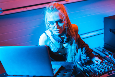attractive blonde dj girl using laptop in nightclubの写真素材