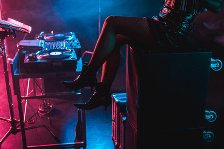 cropped view of dj woman sitting near dj equipment in nightclub with smokeの写真素材