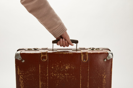 Partial view of woman holding brown suitcase isolated on greyの写真素材