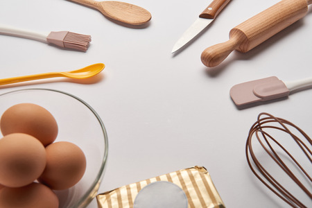 cooking utensils, butter and eggs in bowl on grey surfaceの写真素材