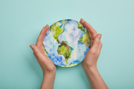 top view of woman holding planet picture on turquoise background, earth day conceptの写真素材