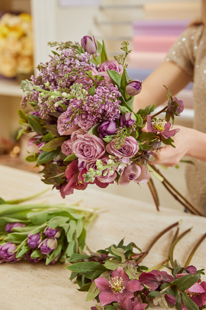 cropped view of woman making bouquet of tulips, peonies and lilac at workplaceの写真素材