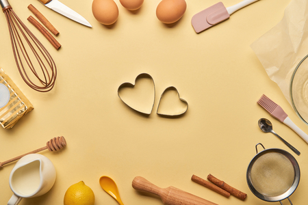 top view of bakery ingredients and cooking utensils around heart shaped dough moldsの写真素材