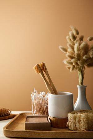 wooden tray with vase of spikelets and different hygiene and care items isolated on brown, zero waste conceptの写真素材
