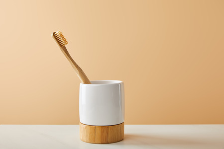bamboo toothbrush in holder on white table and beige backgroundの写真素材