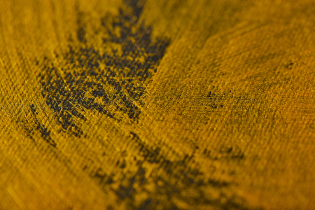 different brushstrokes of golden paint on grey canvas