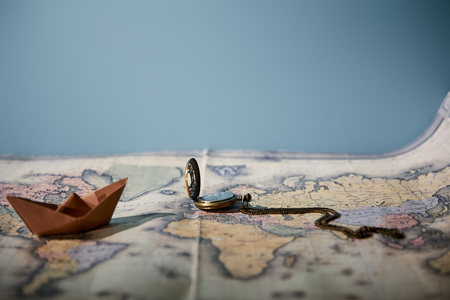 Selective focus of map, compass and paper boat with copy space isolated on blue