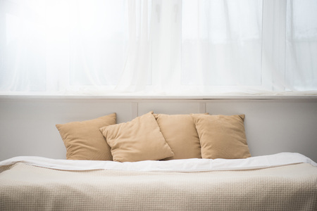 cozy bed with brown pillows and white blanketの写真素材