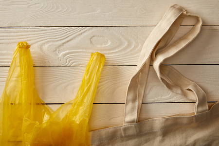 top view of cotton string bag and plastic bag on white wooden surface, zero waste conceptの写真素材