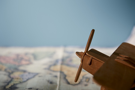 Selective focus of toy plane and map with copy space isolated on blueの写真素材
