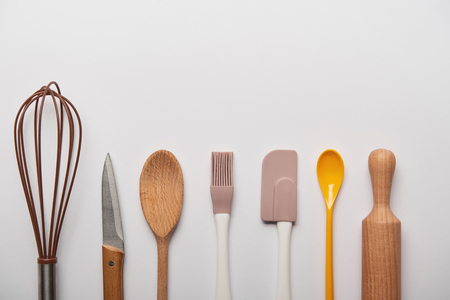 top view of cooking utensils arranged in row on grey backgroundの写真素材