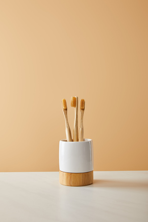 bamboo toothbrushes in holder on white table and beige backgroundの写真素材