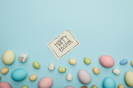 Top view of toy bunny, easter chicken and quail eggs, card with happy easter letteringの写真素材