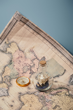 compass, toy ship in glass bottle and world map on blue backgroundの写真素材