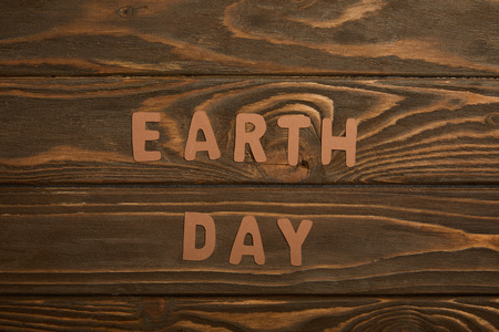 top view of paper letters on brown wooden background, earth day conceptの写真素材