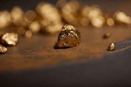 selective focus of golden stones on grey and brown marble surface with blurred backgroundの写真素材