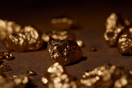 selective focus of golden stones on brown marble backgroundの写真素材