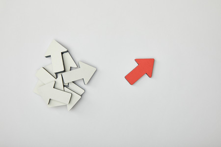 top view of red pointer near bunch of white arrows on grey backgroundの写真素材