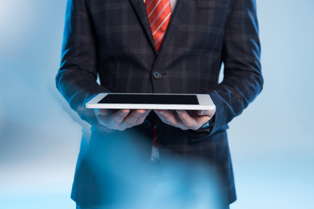 selective focus of businessman holding digital tablet on blueの写真素材