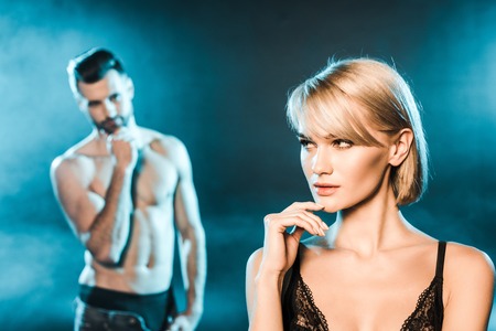 attractive young woman posing with handsome boyfriend on blue smoky backgroundの写真素材