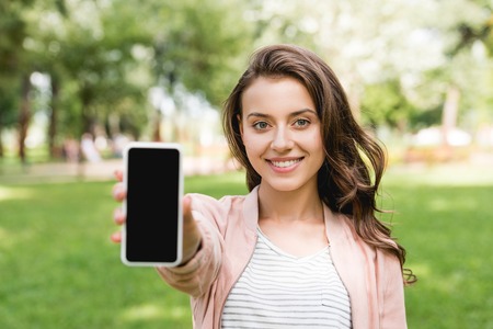 selective focus of attractive girl holding smartphone with blank screenの写真素材