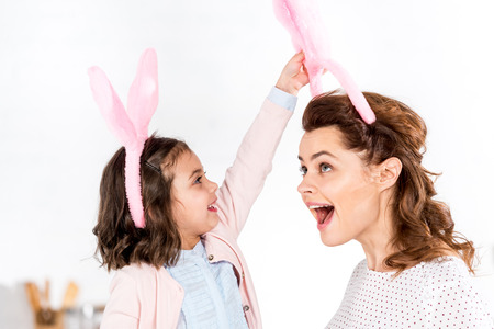 Mother and daughter in bunny ears having fun on whiteの写真素材