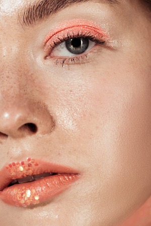 close up of woman with coral glitter makeup looking at cameraの写真素材