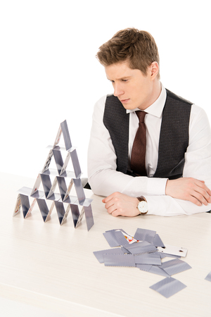 handsome concentrated manager making pyramid from playing cards isolated on whiteの写真素材