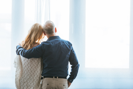 back view of couple hugging near window at home
