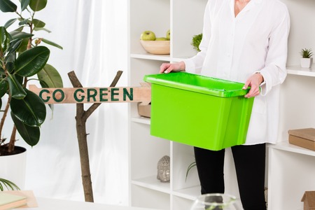 cropped view of woman holding green recycling box near go green sign, environmental saving conceptの写真素材