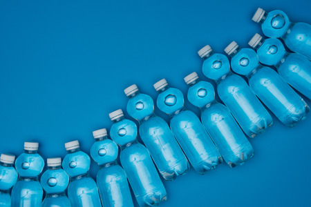 top view of plastic water bottles in row isolated on blue with copy spaceの写真素材