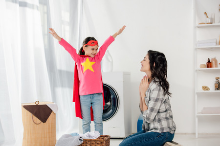 mother sitting on floor near daughter in red homemade suit with star signin laundry roomの写真素材