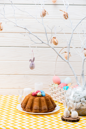 Easter cake with painted eggs and ceramic rabbits on tableの写真素材