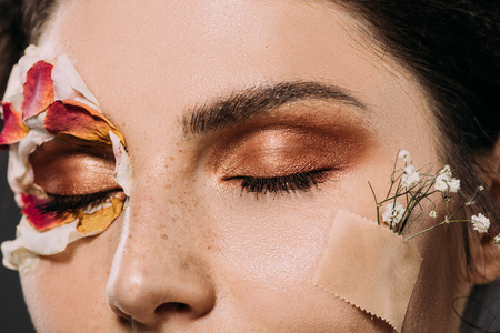 close up of woman with makeup on closed eyes and flowers on faceの写真素材