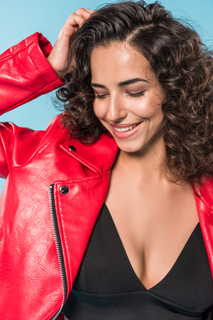 Woman in red leather jacket laughing on blue backgroundの写真素材