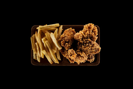top view of tasty french fries and chicken nuggets on plate isolated on blackの写真素材