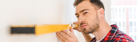 serious man measuring wall at home