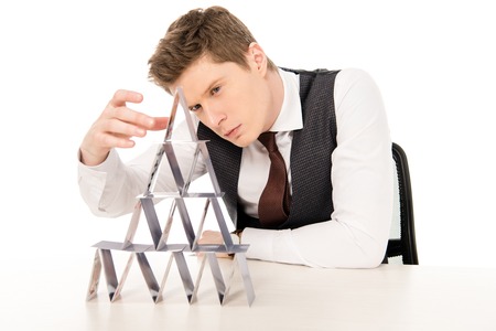 handsome man making pyramid from playing cards isolated on whiteの写真素材