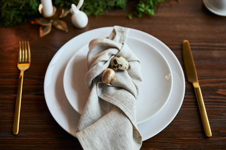 selective focus of quail eggs on napkin and plates near green moss and cutlery on wooden table