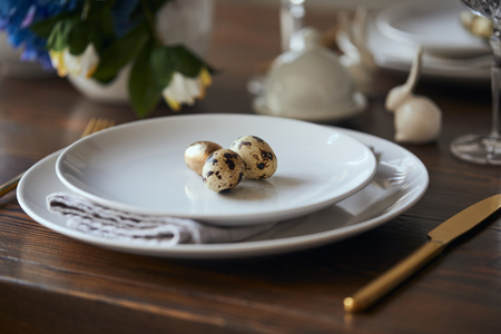 selective focus of quail eggs on white plates and wooden table at home