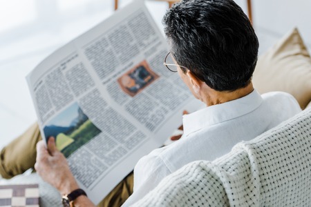 selective focus of man reading newspaper at homeの写真素材