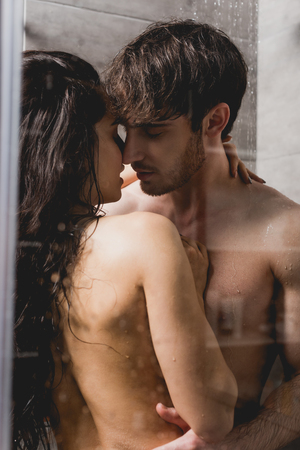 handsome man and beautiful woman hugging in shower cabinの写真素材