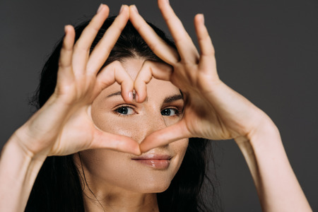 beautiful tender woman showing heart sign isolated on greyの写真素材